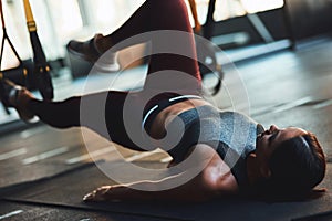 Full Body Workout. Young caucasian athletic woman in sportswear exercising with fitness trx straps at industrial gym