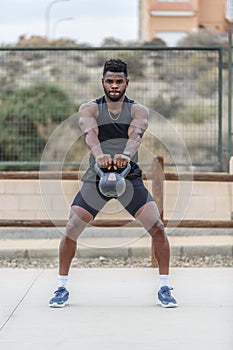 Black sportsman doing kettlebell swing exercise