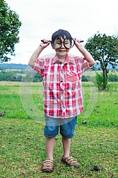 Full body. Young boy exploring nature with magnifying glass. Out
