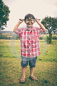 Full body. Young boy exploring nature with magnifying glass. Out