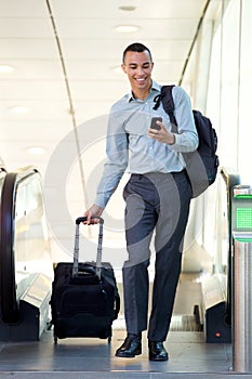 Full body young businessman walking with travel bags and mobile phone
