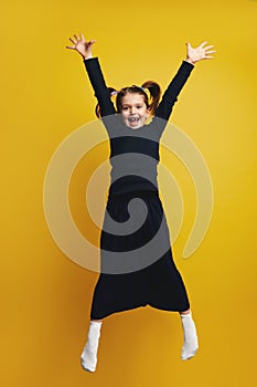 Full body of young cute girl smiling and raising hands up while jumping