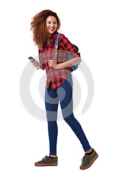 Full body young woman walking on white background with mobile phone and bag