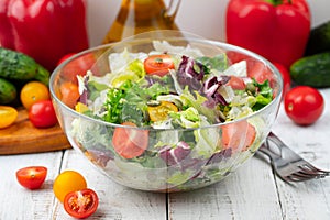 Full bowl of fresh green salad close up on a light table against a white background on a rustic kitchen. Concept helpful and simpl