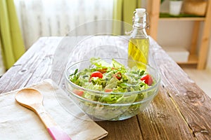 Full bowl of fresh green salad on a wooden table against on a rustic kitchen. Concept healthy lifestyle and simple food