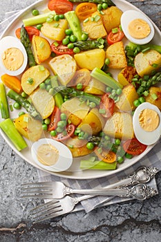 Full breakfast Fried new potatoes with asparagus, cherry tomatoes, hard-boiled egg and green peas close-up in a plate on the table