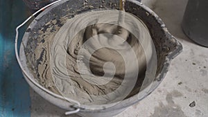 A full bucket of special tile adhesive ready for use. Dense cement-based adhesive mixer. The tile adhesive is mixed in a