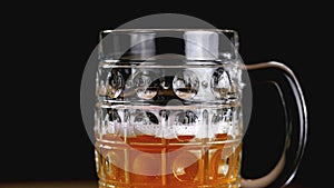 Full circle amber beer on a black background. Slow motion. Beer mug np half empty.