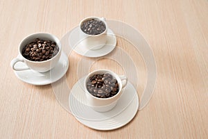 Full coffee beans cups on the wood background