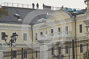 Silhouettes of people are visible on the roof of a large building. photo