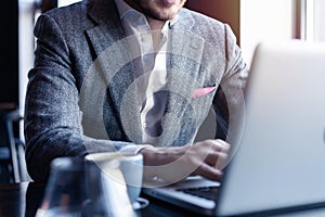 Full concentration. Good looking young man in full suit using computer while sitting in the cafe