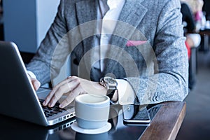 Full concentration. Good looking young man in full suit using computer while sitting in the cafe