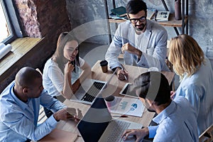 Full concentration at work. Group of young business people working and communicating while sitting at the office desk