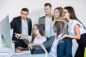 Full concentration at work. Group of young business people working and communicating while sitting at the office desk together