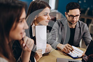 Full concentration at work. Group of young business people working and communicating while sitting at the office desk together