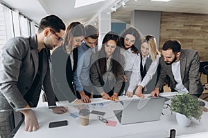 Full concentration at work. Group of young business people working and communicating while standing in modern office