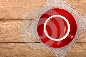 Full cup of black tea in red cup on wooden table