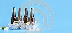 Full dark bottles of beer without labels, with cubes of ice and with lime pieces with flowing drops