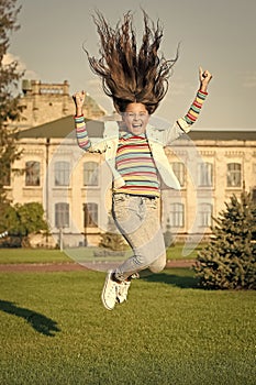 full of energy. childhood happiness. small girl with curly hair jump outdoor. spring holiday celebration. child fly in