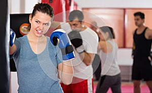 full of energy sportswoman in the boxing hall practicing boxing punches with boxing bag