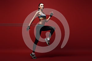 Full of energy. Sportswoman jumping with resistance band over red background,