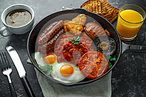 Full English breakfast with bacon, sausage, fried egg, baked beans, hash browns and mushrooms in rustic skillet, pan