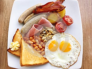 Full English breakfast with fried eggs, sausages, bacon, beans and toasts