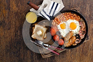 Full English breakfast with orange juice on rustic wooden background