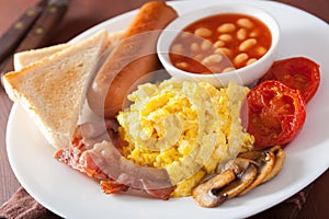 full english breakfast with scrambled eggs, bacon, sausage, beans, tomato