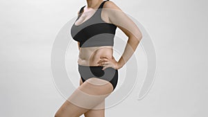 Full figure body positive caucasian woman in black underwear turns around and appreciate her body. White studio
