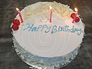 White birthday cake with lit candles