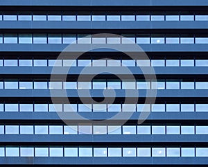 Full frame image of a large commercial building with repeating rows of geometric windows