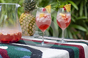 Full Frame image of two Glasses of Sangria on a Multicolored Cloth with Lady Palms in the Background.