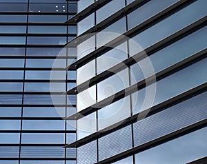 Full frame modern office architecture abstract with geometric shapes of tall buildings reflecting the blue sky in large glass