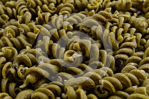 Full frame of wholegrain spiral pasta with spinach.