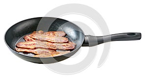 full frying pan of fried bacon isolated on white background. Macro photo of bacon being fried in a pan