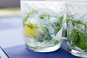 Full glass of fresh cool transparent water with ice, lemon and , basil leaves