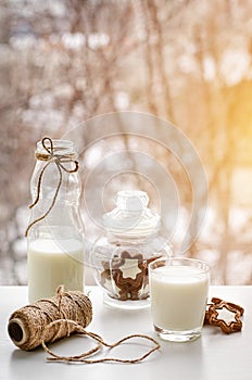 Full glass of milk, chocolate cookies and a bottle on breakfast table