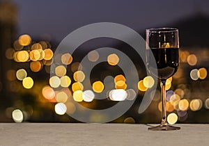 Full glass of red wine over a stone table and in front of a city photo