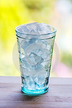 Full glass of water with ice on the wooden kitchen counter.