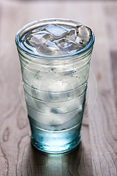 Full glass of water with ice on the wooden kitchen counter. Wodden background.