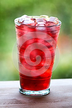 Full glass of water and juice with ice on the wooden kitchen counter.