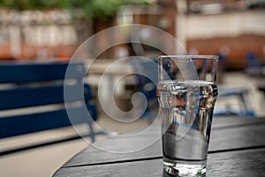 Full glass of water sitting on wooden picnic table in restaurant