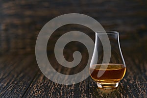 Full glass of whiskey on a wooden table, selective focus with copy space