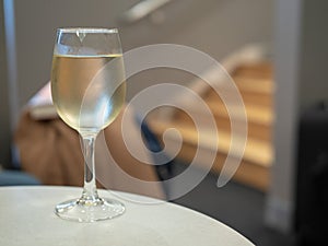 Full glass of white wine sitting on table inside a airport lounge