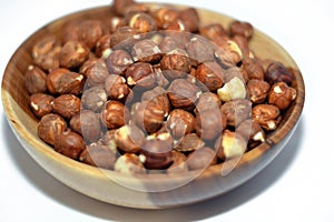 Full hazelnuts in a brown wooden bowl  on white background, selective focus