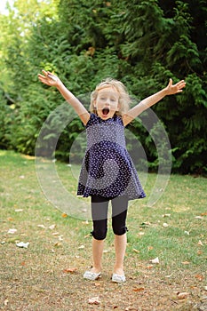 Full Height Outdoors Portrait of Happy Acive Blonde Girl Screaming in the Park During Summer Day