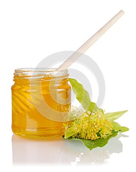 Full jar with linden honey, honey dipper and flowering linden on white