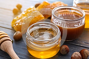 Full jars of honey with honeycomb on wooden table, closeup