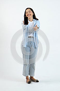 full leght shoot of happy asian indonesian woman holding phone and showing blank screen on isolated background